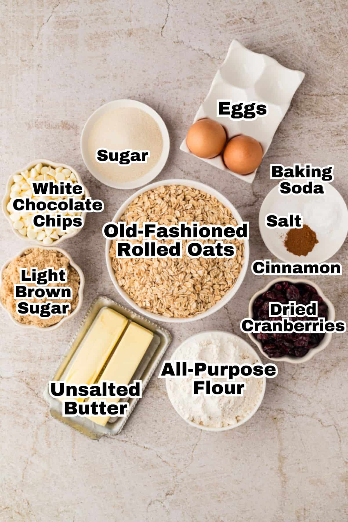 The ingredients to make oatmeal cranberry cookies in small individual bowls.