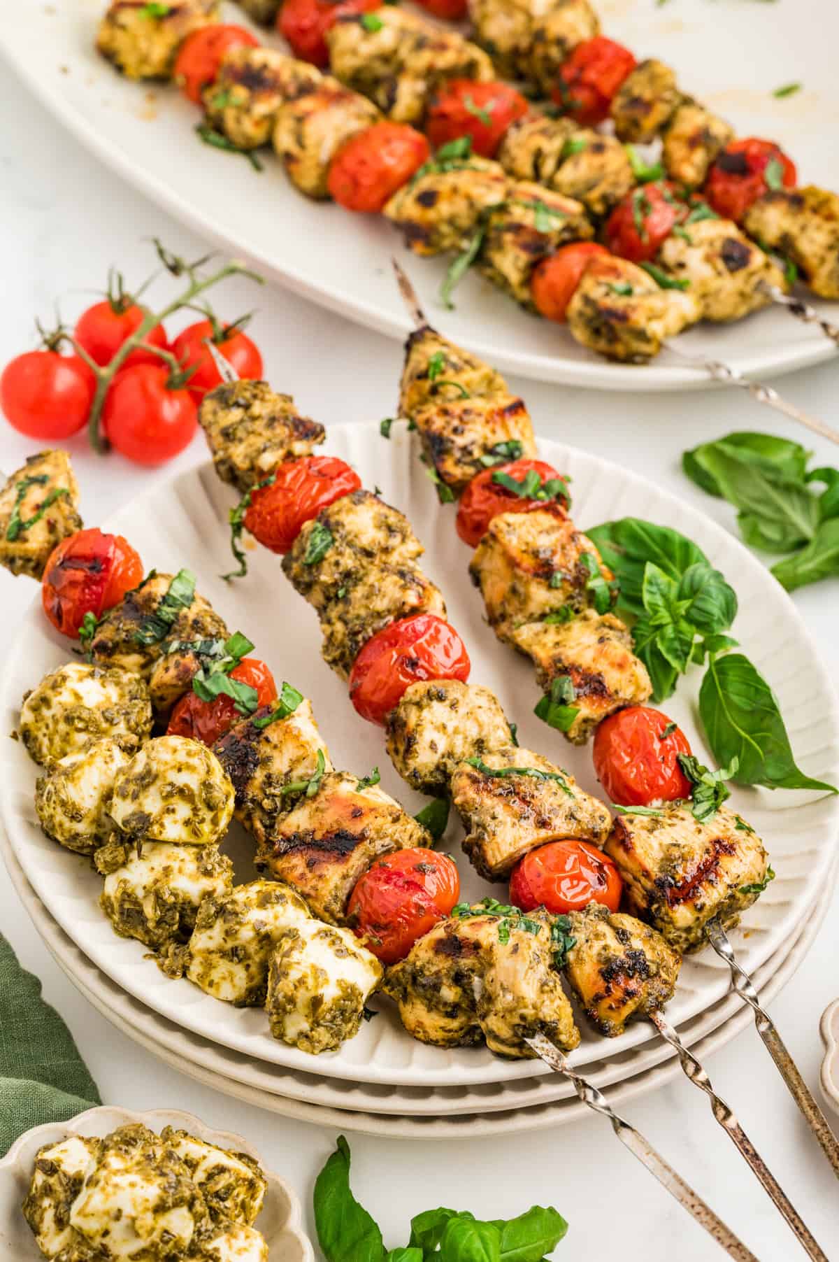 Pesto chicken skewers with cherry tomatoes and mini mozzarella balls also covered in pesto sauce.