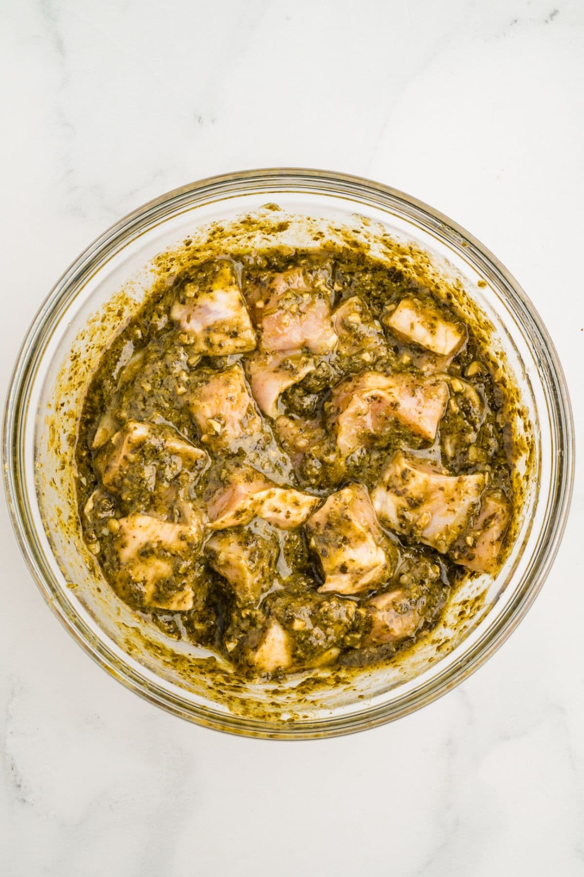 The chicken pieces are marinating in pesto sauce.
