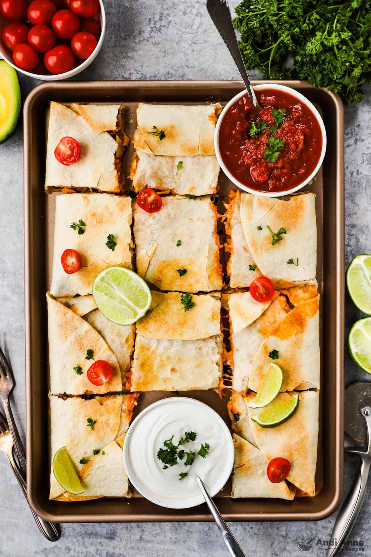 sheet pan quesadillas recipe with bowls of salsa and sour cream