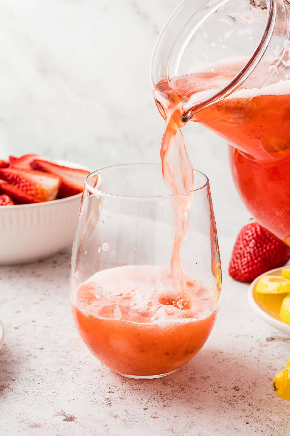 Sparkling strawberry lemonade is being poured into a glass.