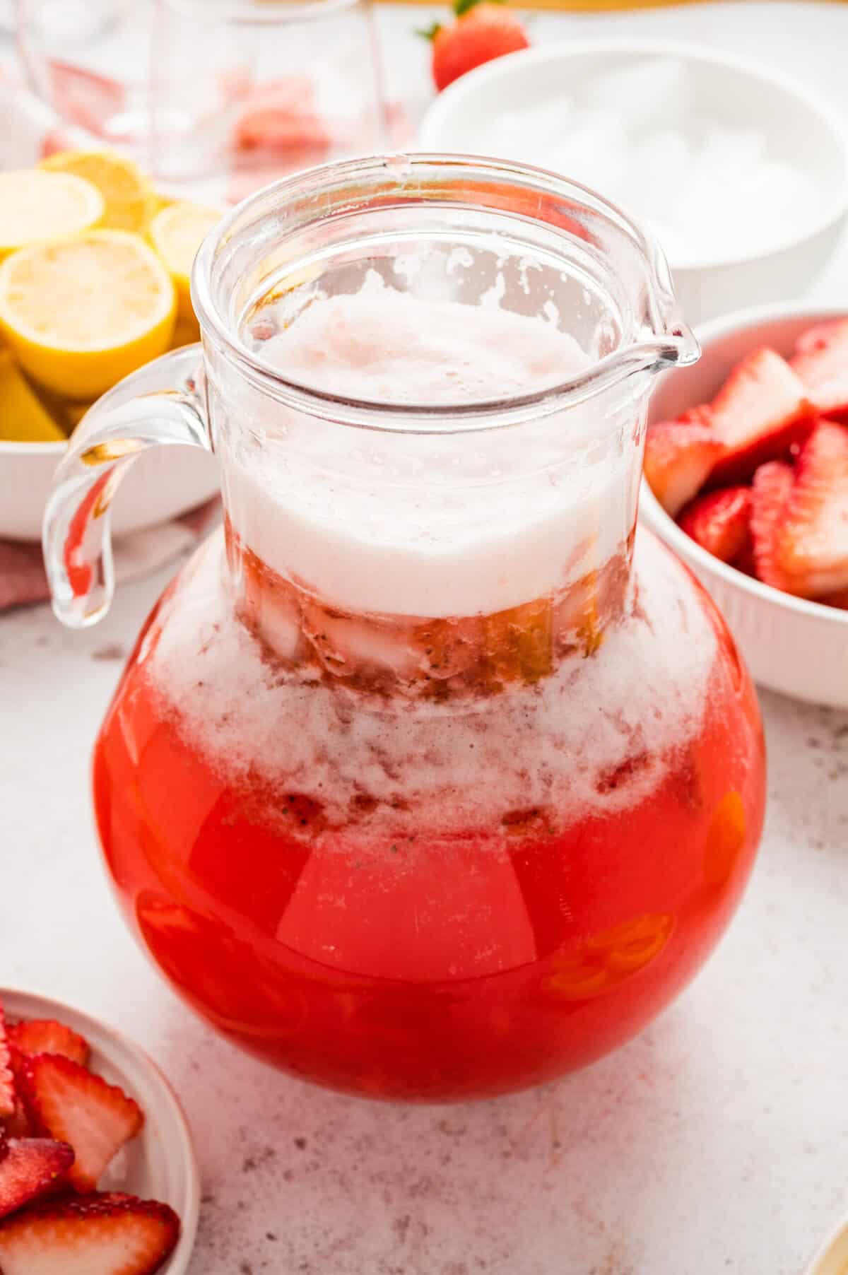 A large pitcher is filled with sparkling strawberry lemonade.