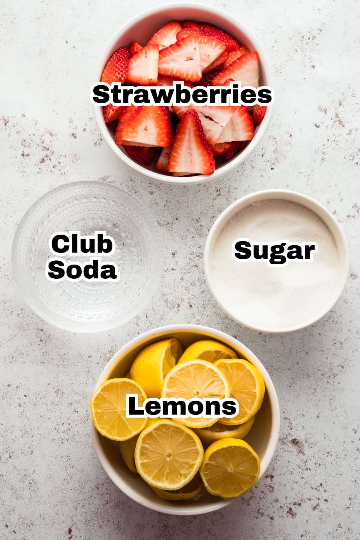 Strawberries, lemons, club soda, and sugar are in individual bowls.
