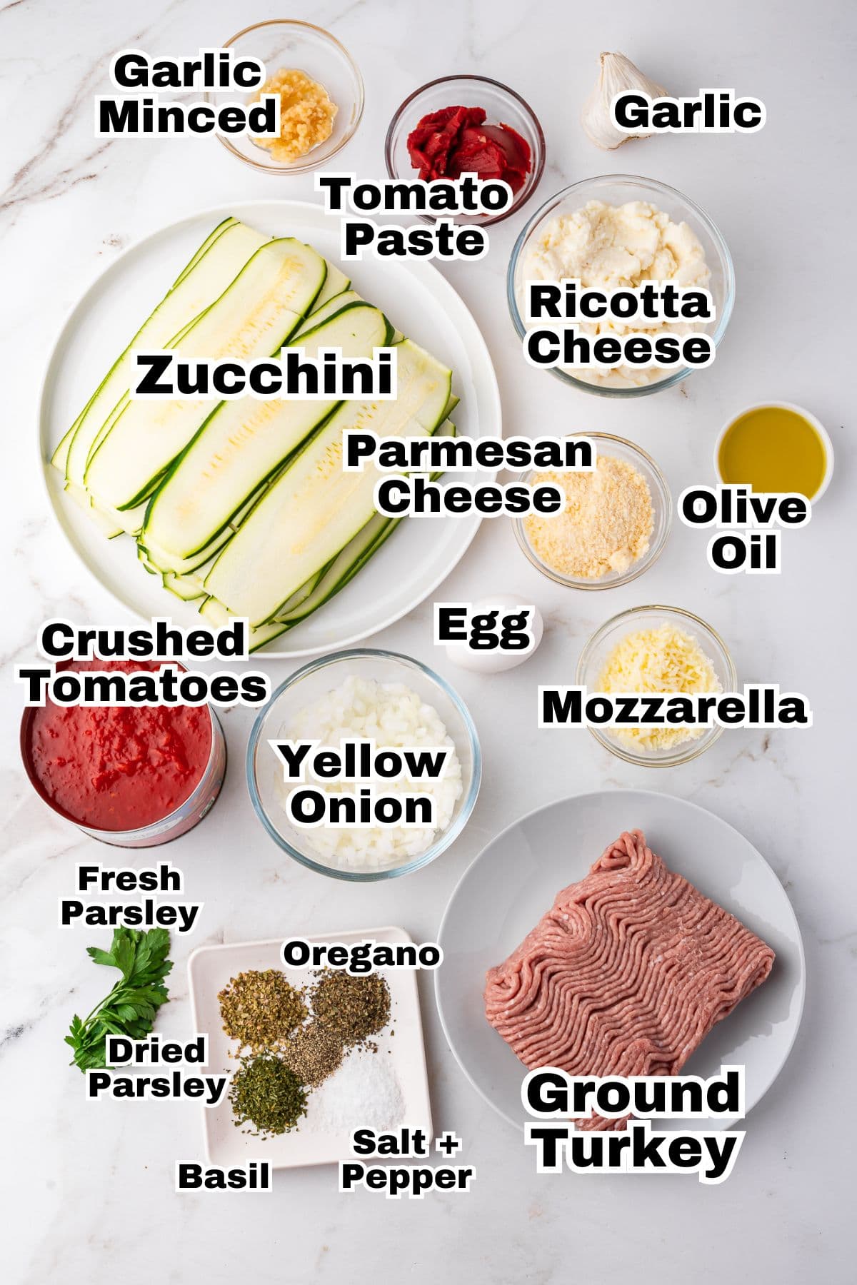 The ingredients to make zucchini lasagna are in individual bowls.