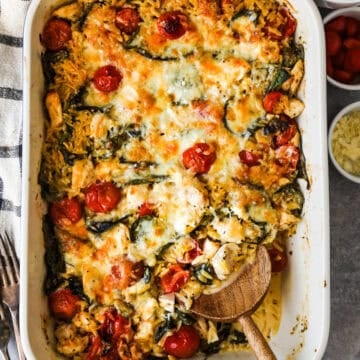 Baked greek chicken and orzo casserole in the pan with a serving removed.