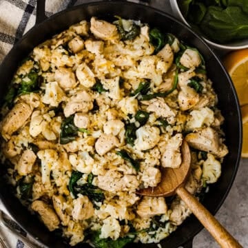 Lemon chicken, rice, cauliflower, and spinach in a skillet.
