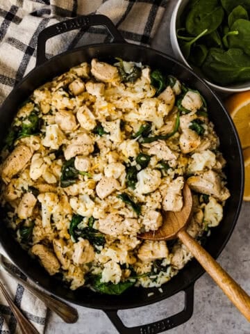 Lemon chicken, rice, cauliflower, and spinach in a skillet.