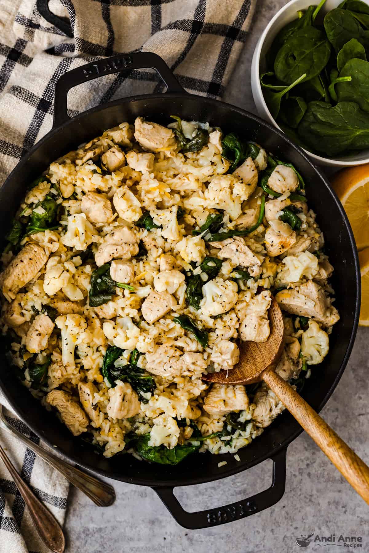 Lemon chicken, rice, cauliflower, and spinach in a skillet.