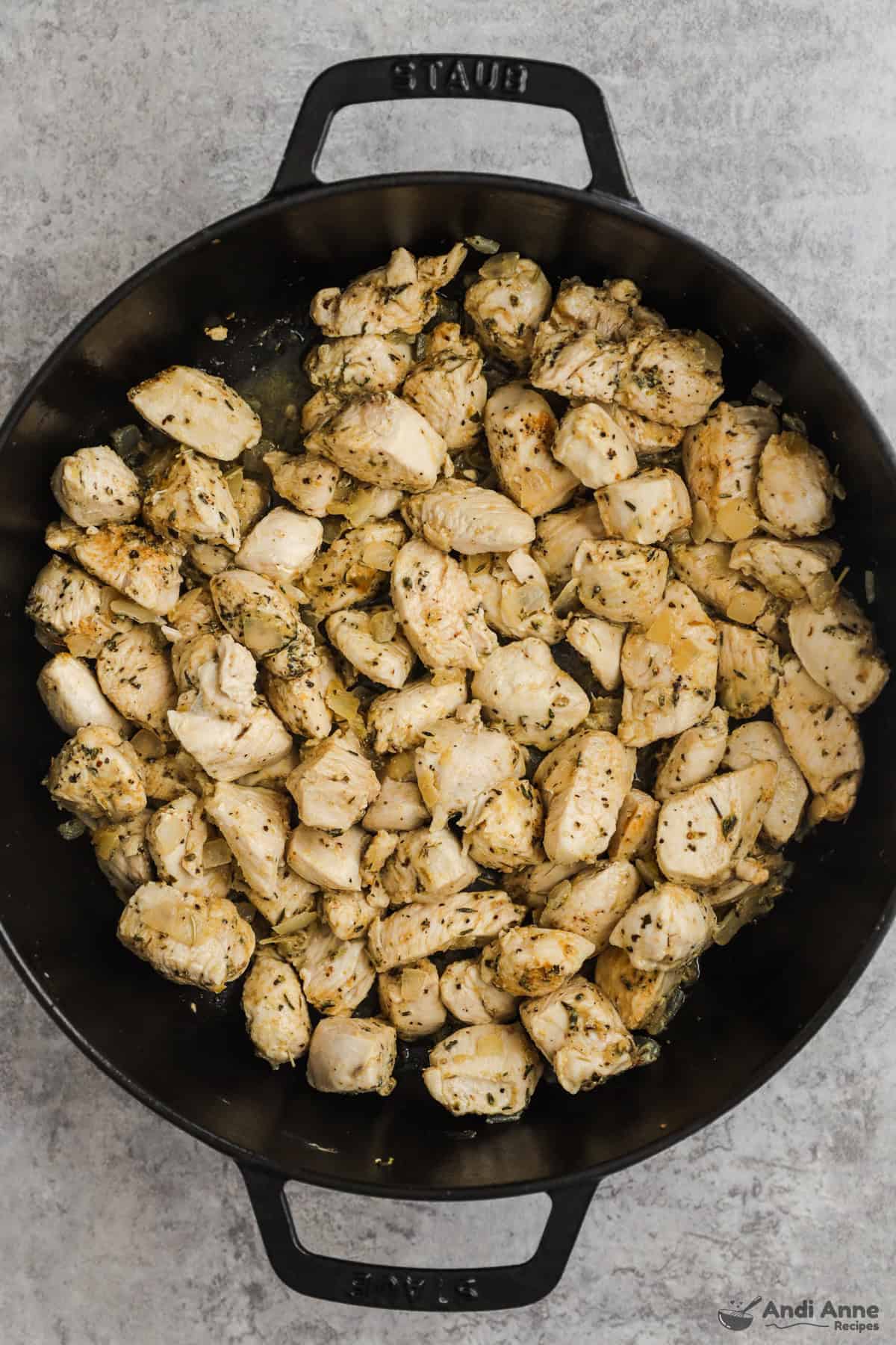 Chopped chicken, Italian seasoning, garlic powder, paprika, and black pepper are cooked in a large skillet.