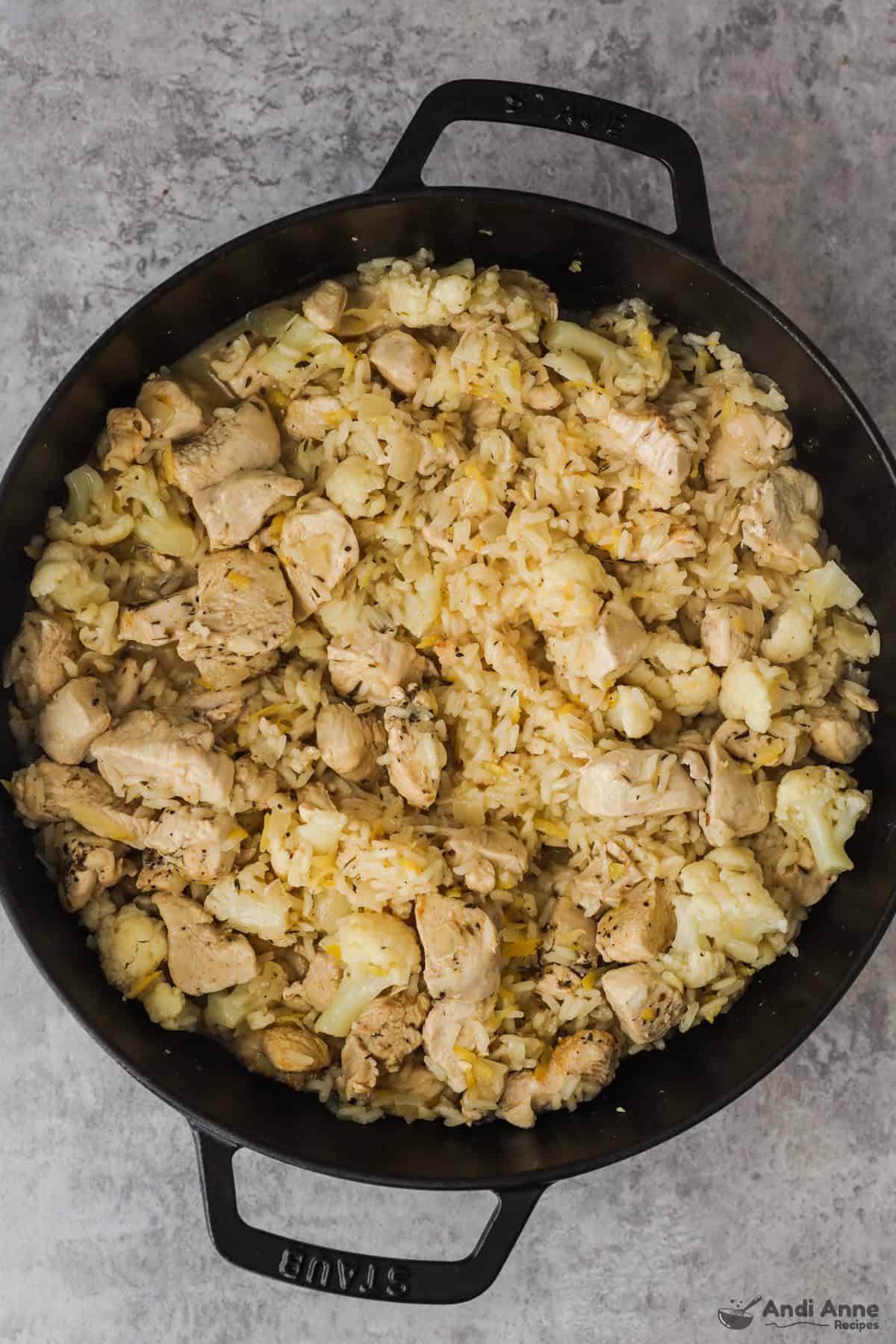 Cauliflower, lemon juice, lemon zest, rice, and chicken after cooking in the skillet.
