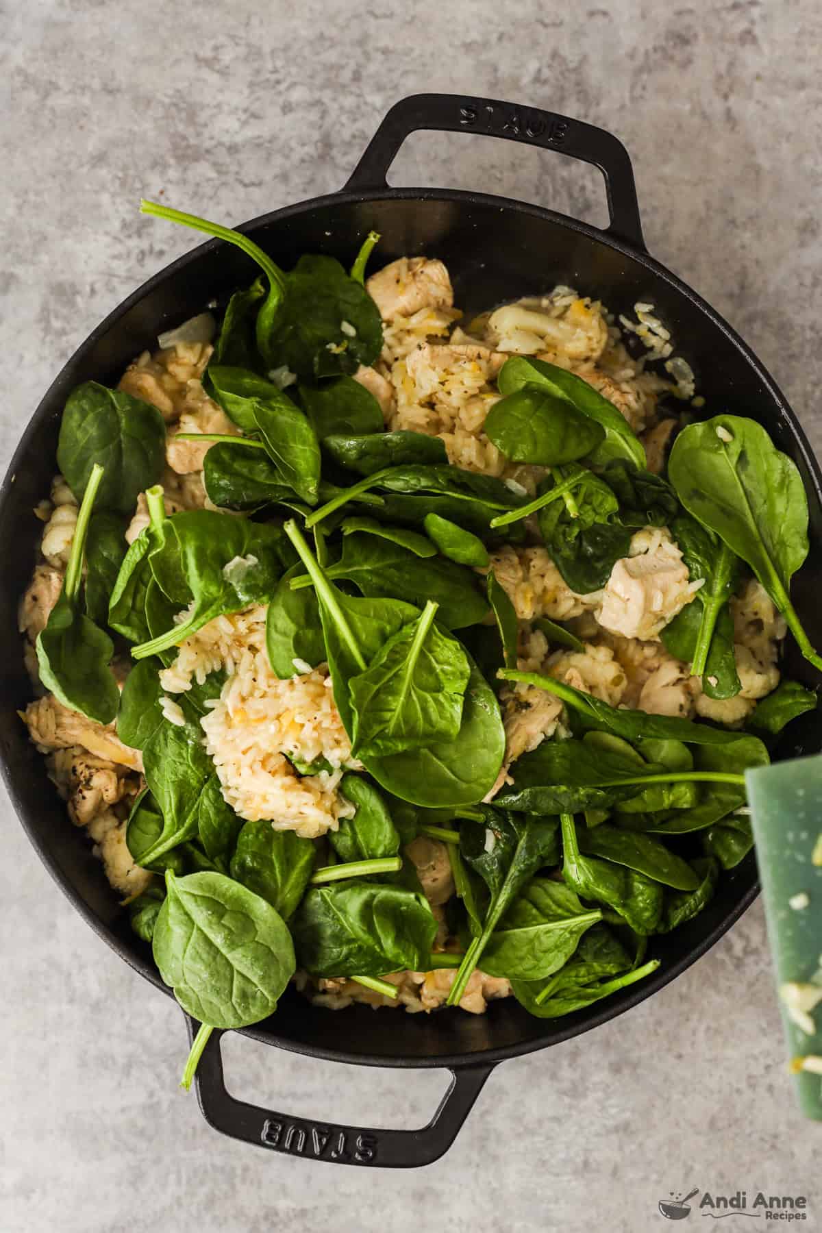 Baby spinach is added to the skillet with chicken, rice, and cauliflower.