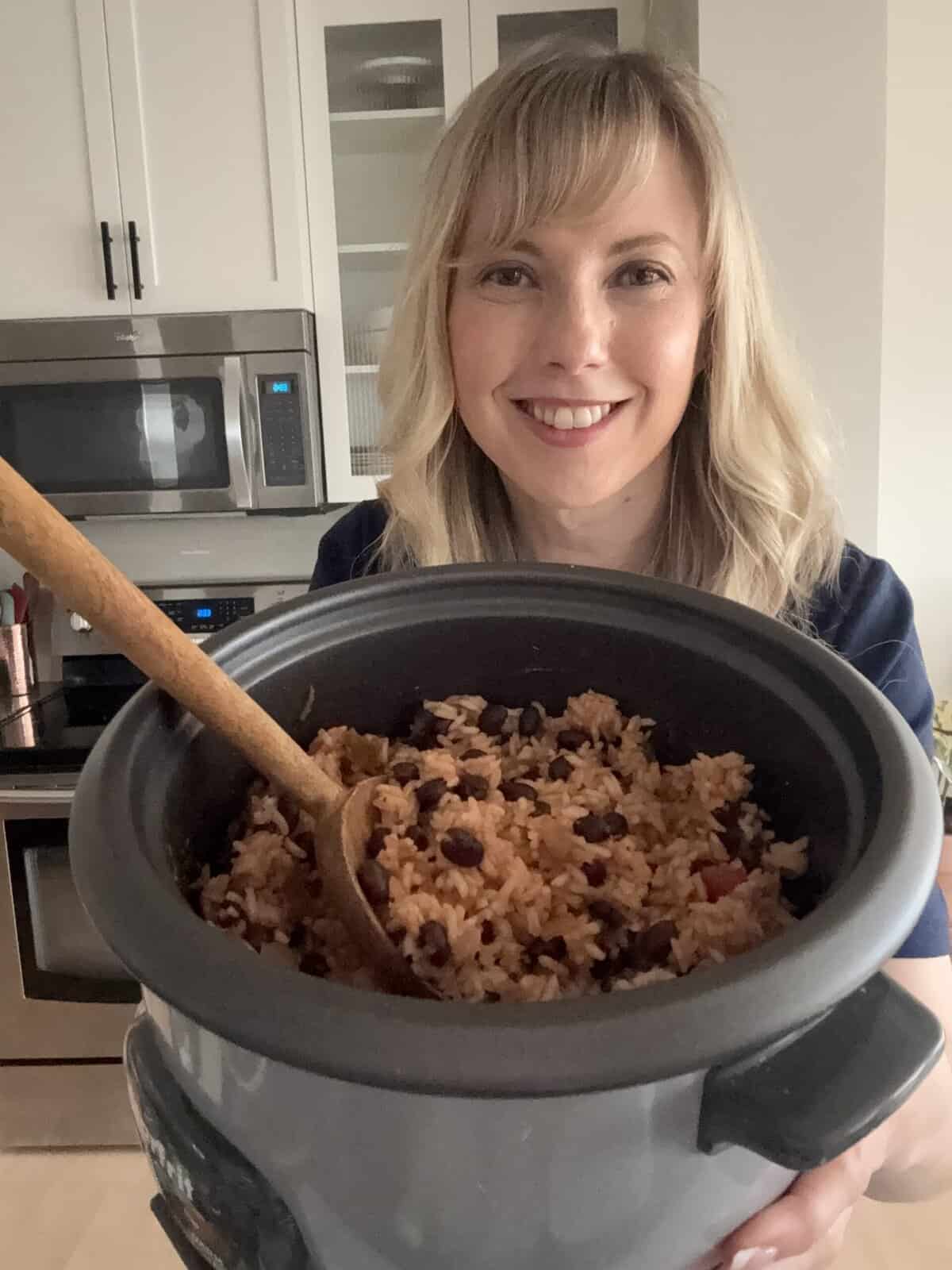 A rice cooker is used to cook rice, black beans, and spices together.