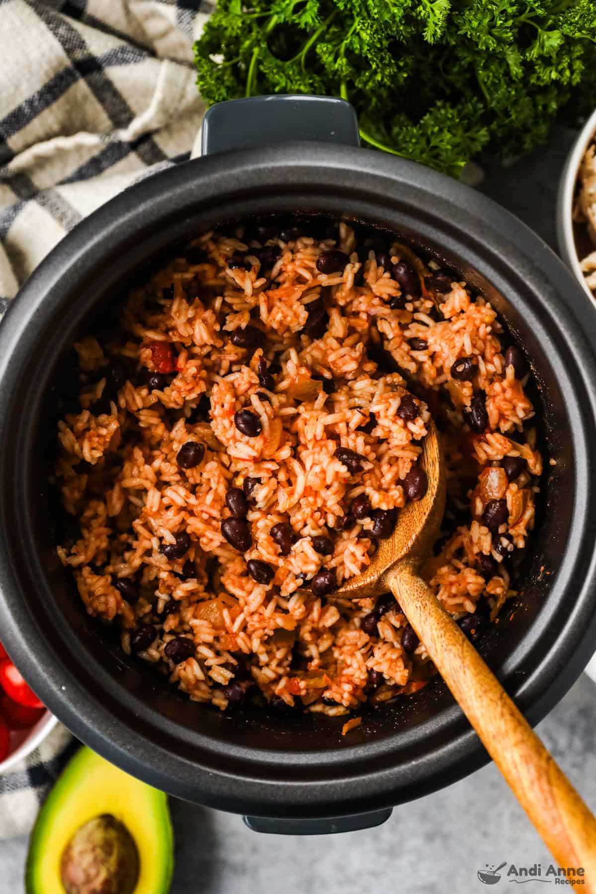 A wooden spoon is stirring the black bean and rice made in the rice cooker.