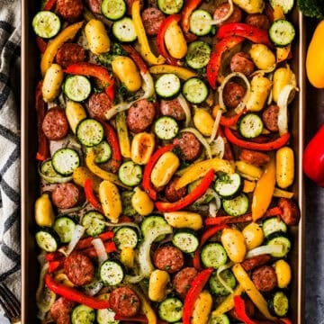 A sheet pan meal with smoked sausage, zucchini, bell peppers, onions, and gnocchi.