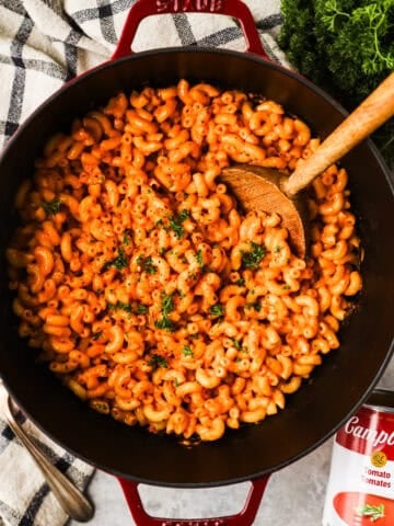 Tomato soup mac and cheese in a large pot with a wooden spoon.