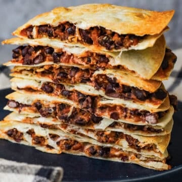A stack of quesadillas that are filled with black beans, melted cheese, and salsa.