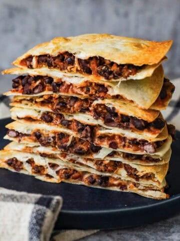 A stack of quesadillas that are filled with black beans, melted cheese, and salsa.