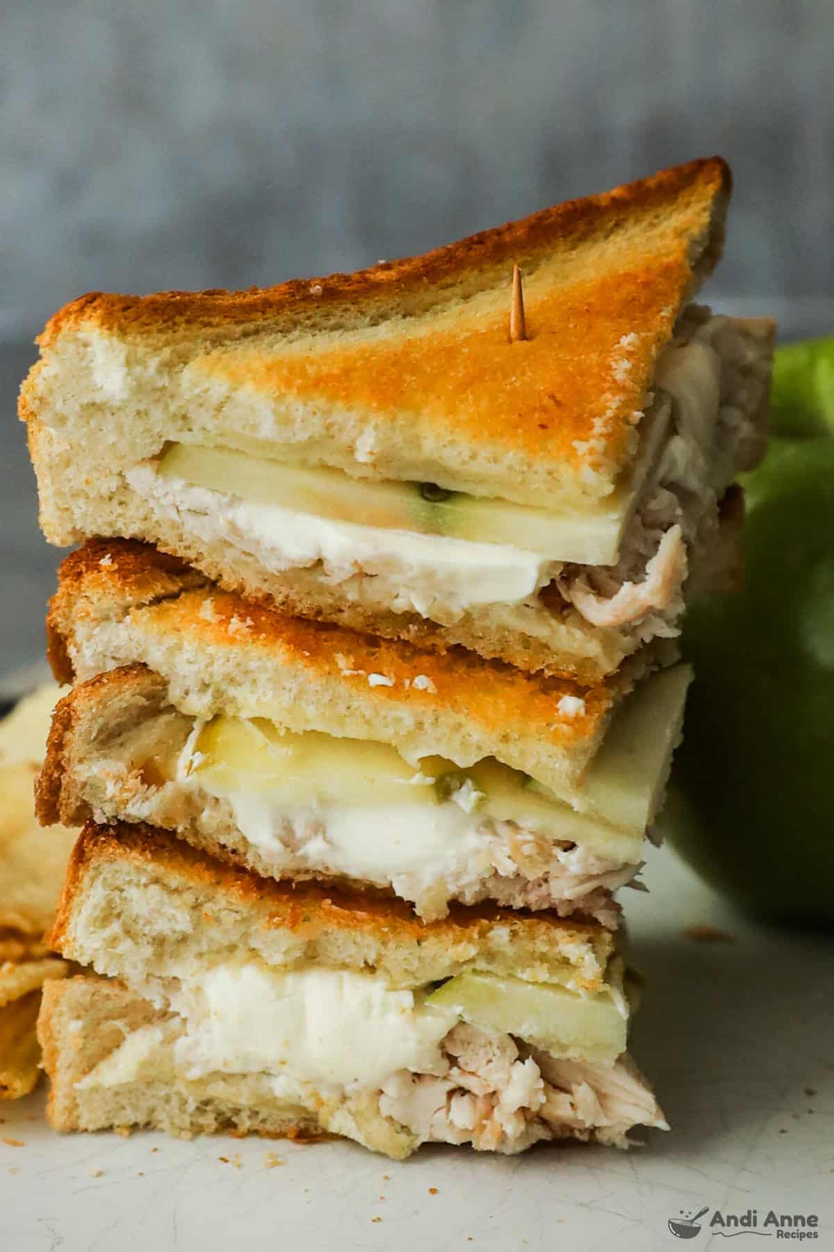 Chicken and apple sandwiches with cream cheese are cut into triangles and stacked.