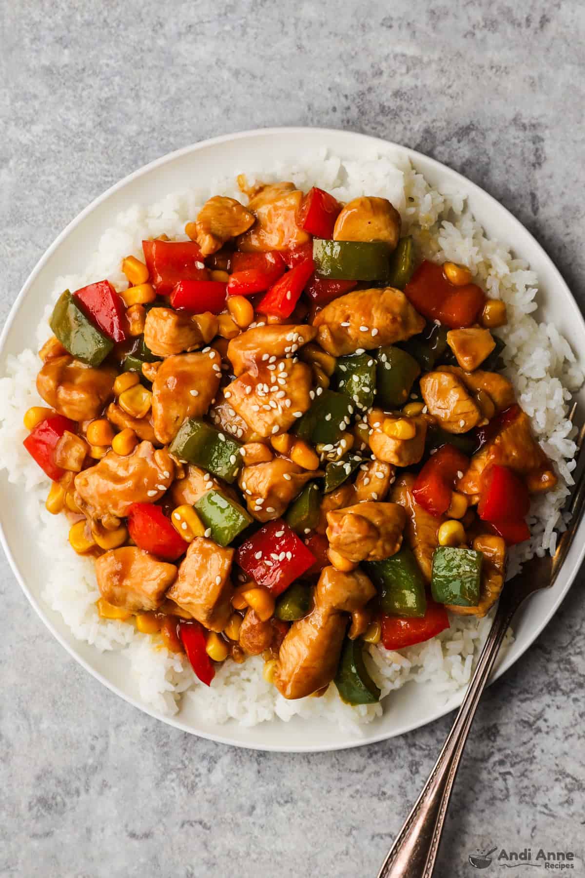 Kung pao chicken on a bed of rice topped with sesame seeds.