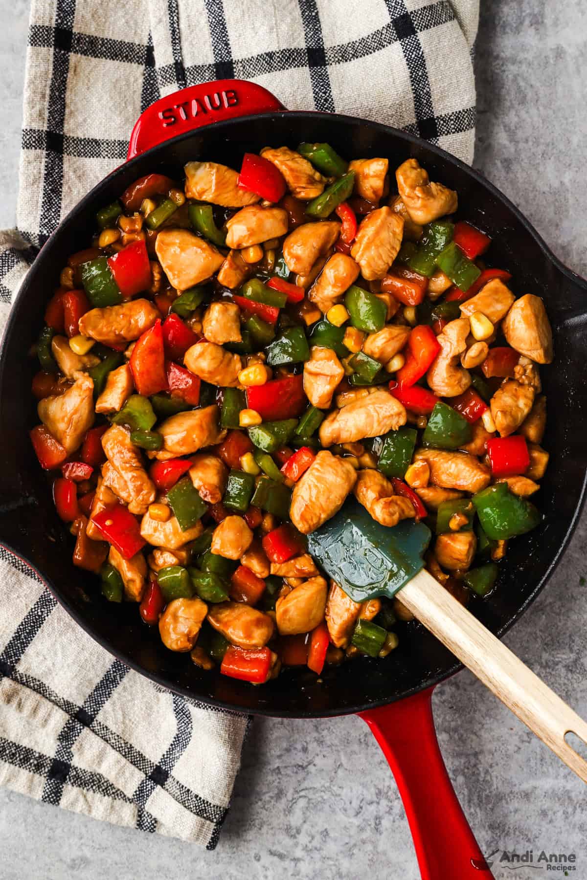 Kung pao chicken in a skillet with red and green bell peppers.