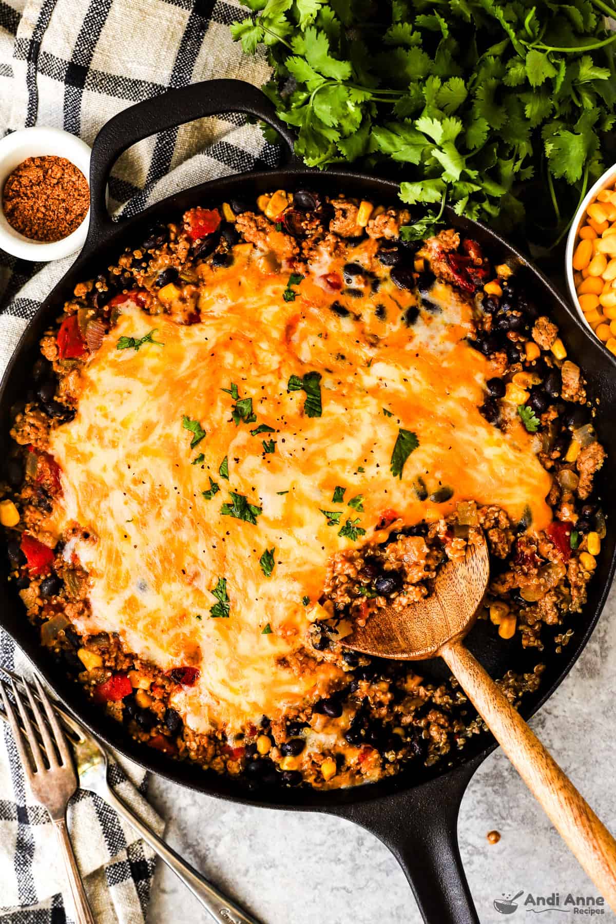 A skillet with taco seasoned ground turkey, quinoa, black beans, salsa, and topped with melted cheese.