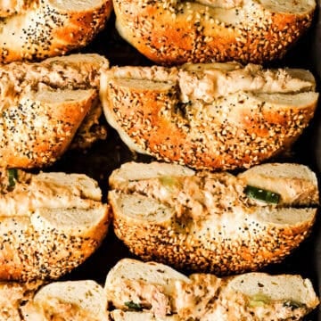 Tuna melt bagels cut in half on a sheet pan.