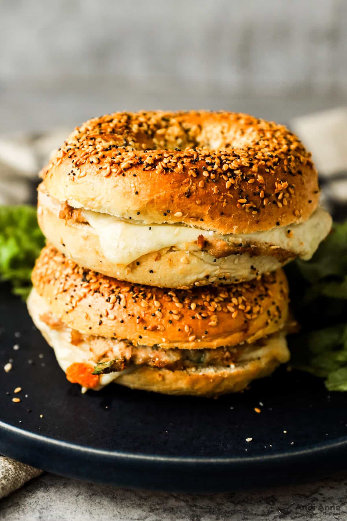 Two tuna bagel melts stacked on a plate.