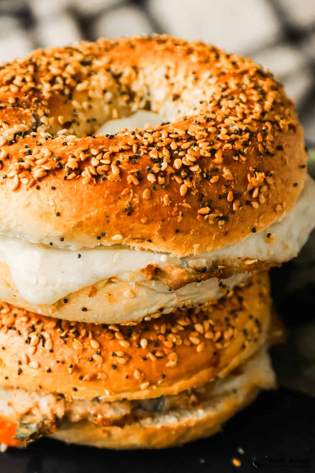 A close-up of two bagel tuna melts stacked on a plate.