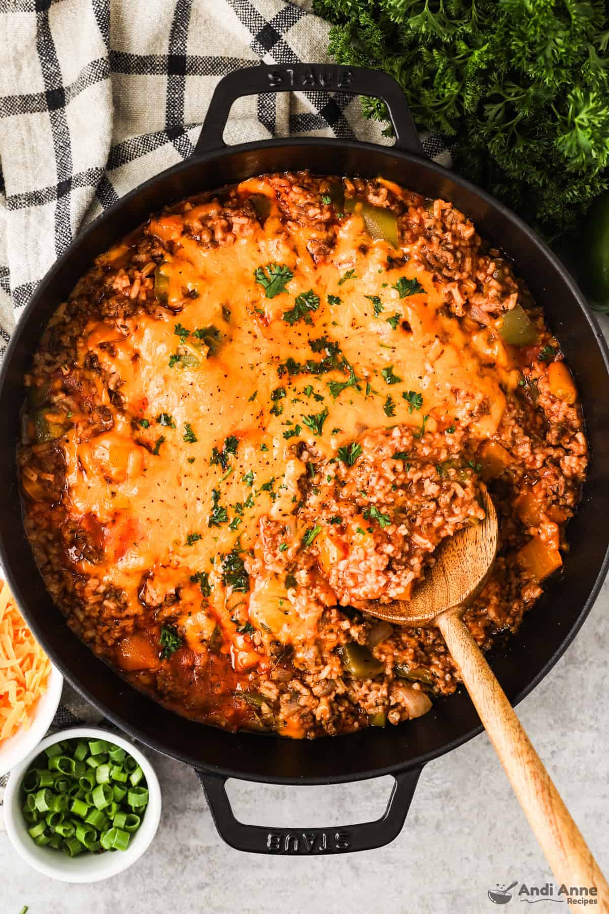 A skillet with ground beef, rice, bell peppers, and tomato sauce topped with melted cheese.
