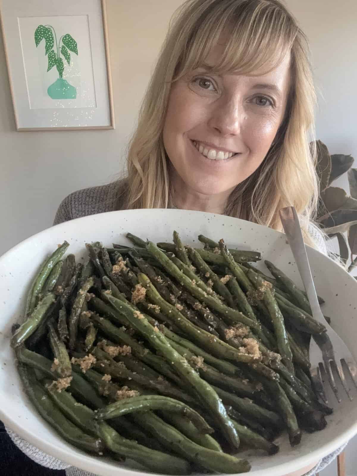 Andi is holding a serving dish of brown sugar green beans.