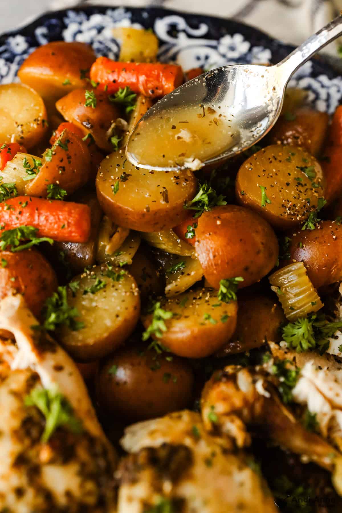 The drippings from the roasted chicken are spooned over the cooked vegetables.