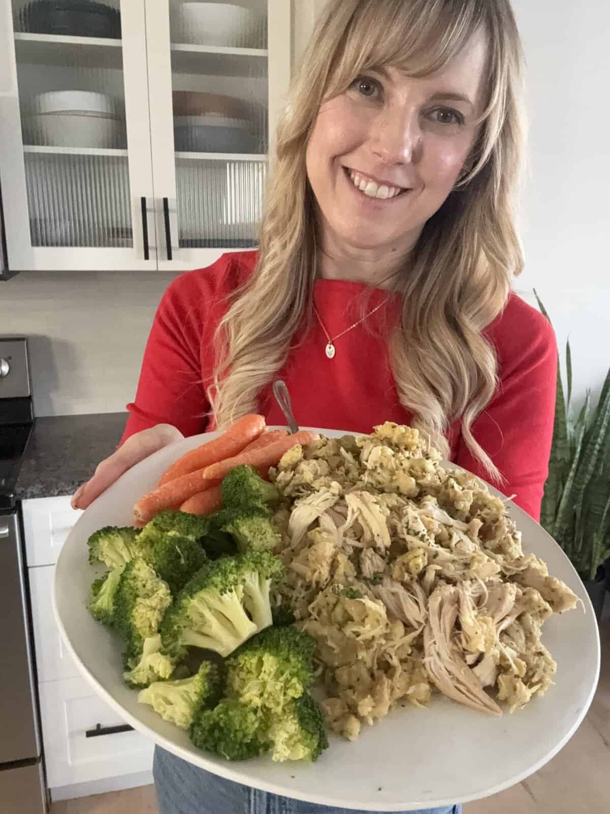 andi holding plate with broccoli, carrots, and chicken and stuffing