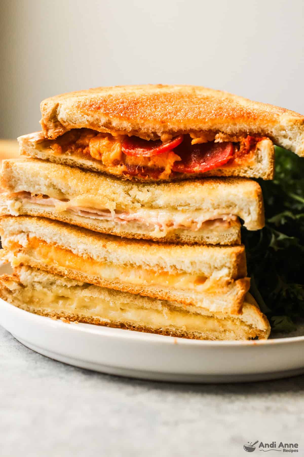 Slices of four different grilled cheese sandwiches in a stack.