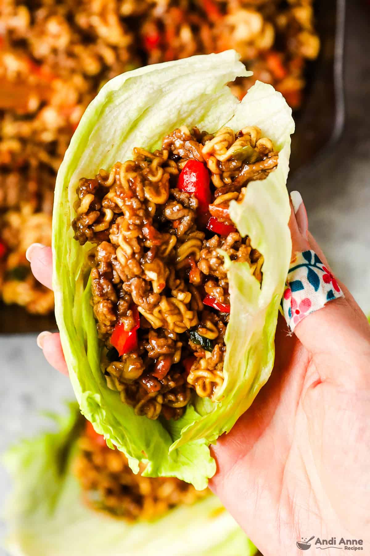 A lettuce wrap with ground beef, ramen noodles, and vegetables in a teriyaki sauce.