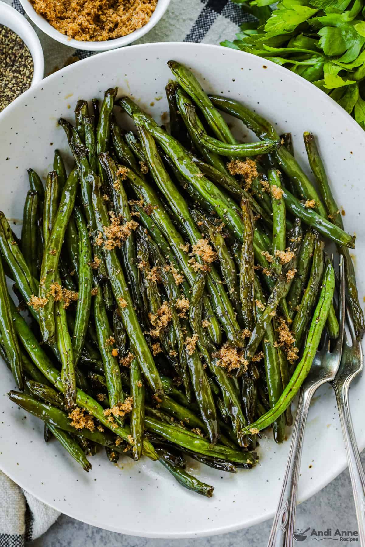 Brown sugar green beans topped with a sprinkle of extra brown sugar on a serving dish with two forks.