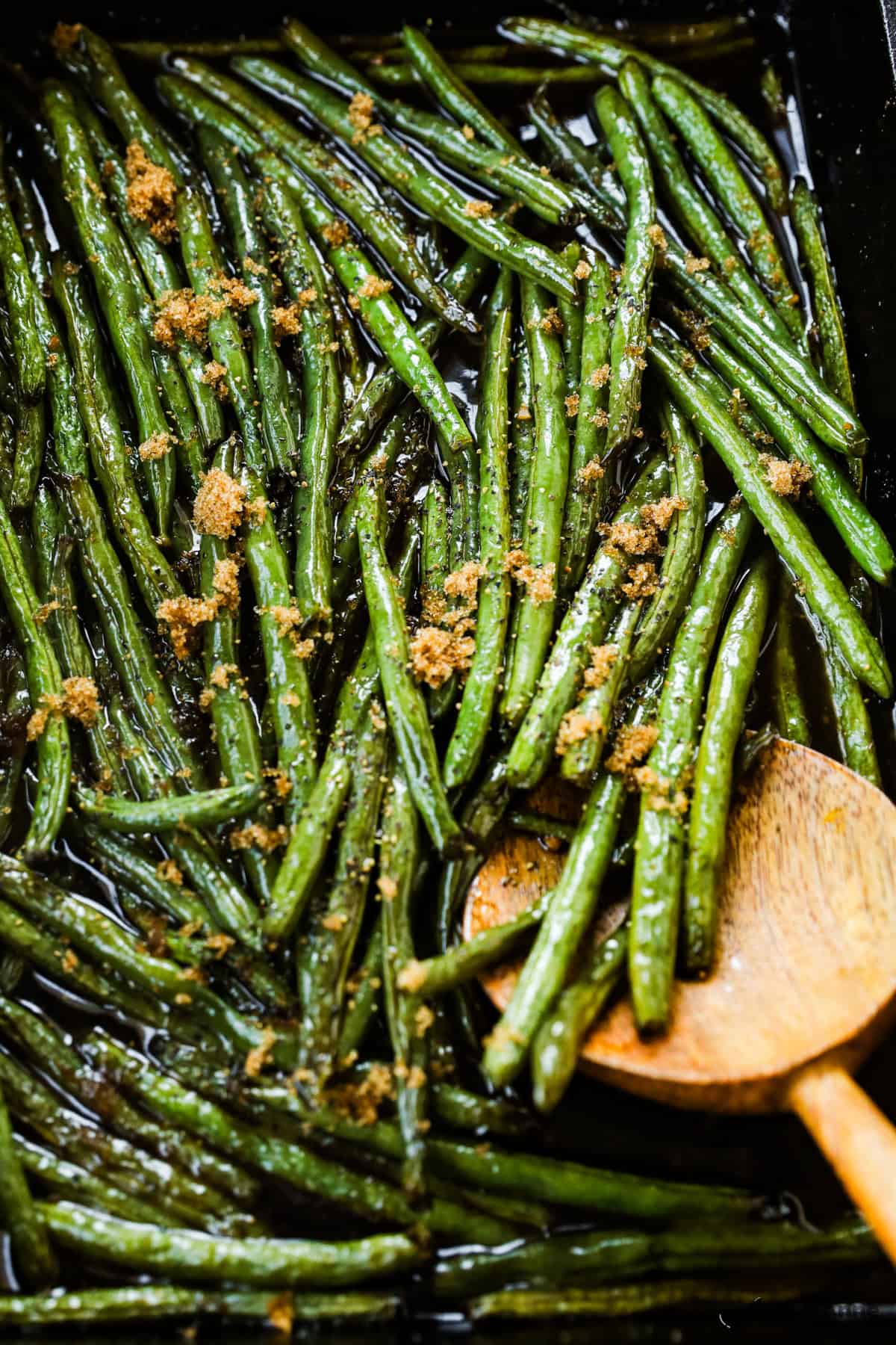 A close-up of roasted green beans with a sprinkle of brown sugar.