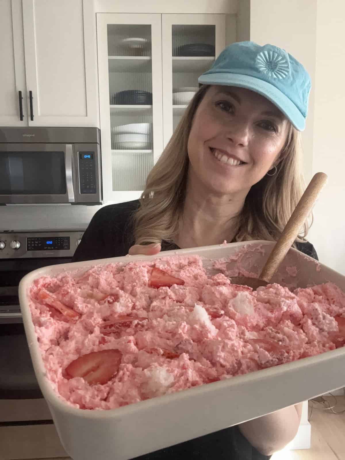 Andi is holding a pan of strawberry angel food cake dessert.