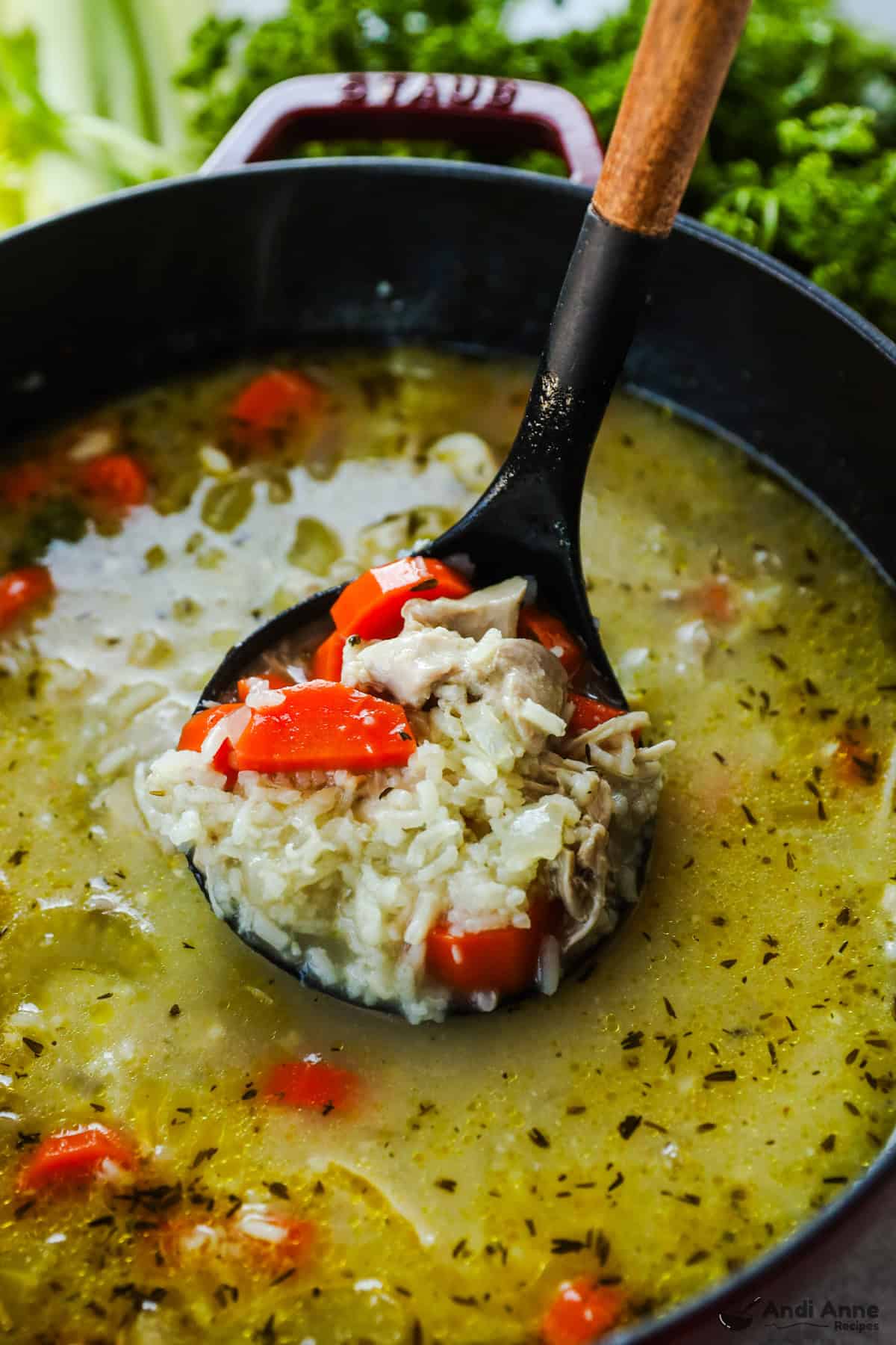 A ladle is holding a scoop of chicken and rice soup.