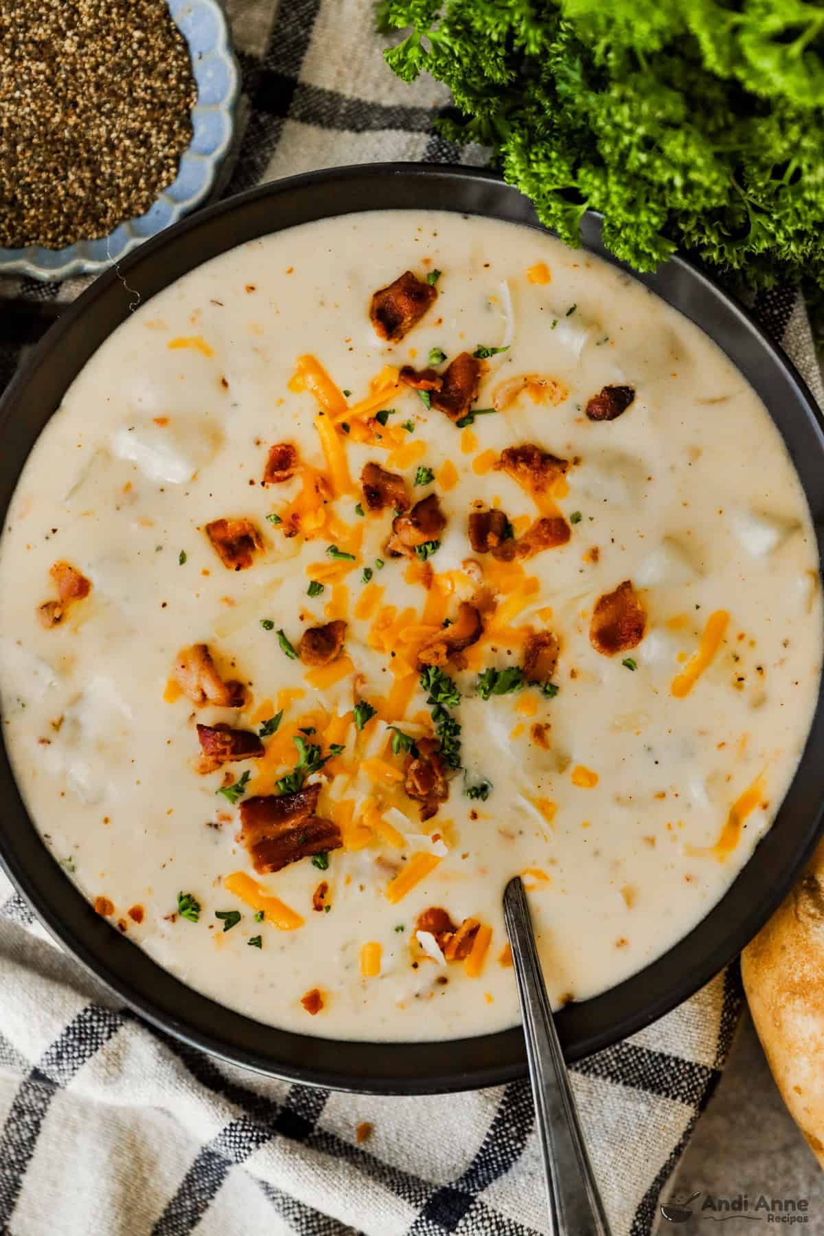 A large bowl of baked potato soup loaded with bacon, cheddar cheese, and chives.