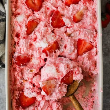 A baking dish with strawberry angel food cake dessert topped with sliced strawberries.