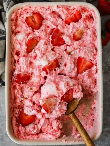 A baking dish with strawberry angel food cake dessert topped with sliced strawberries.