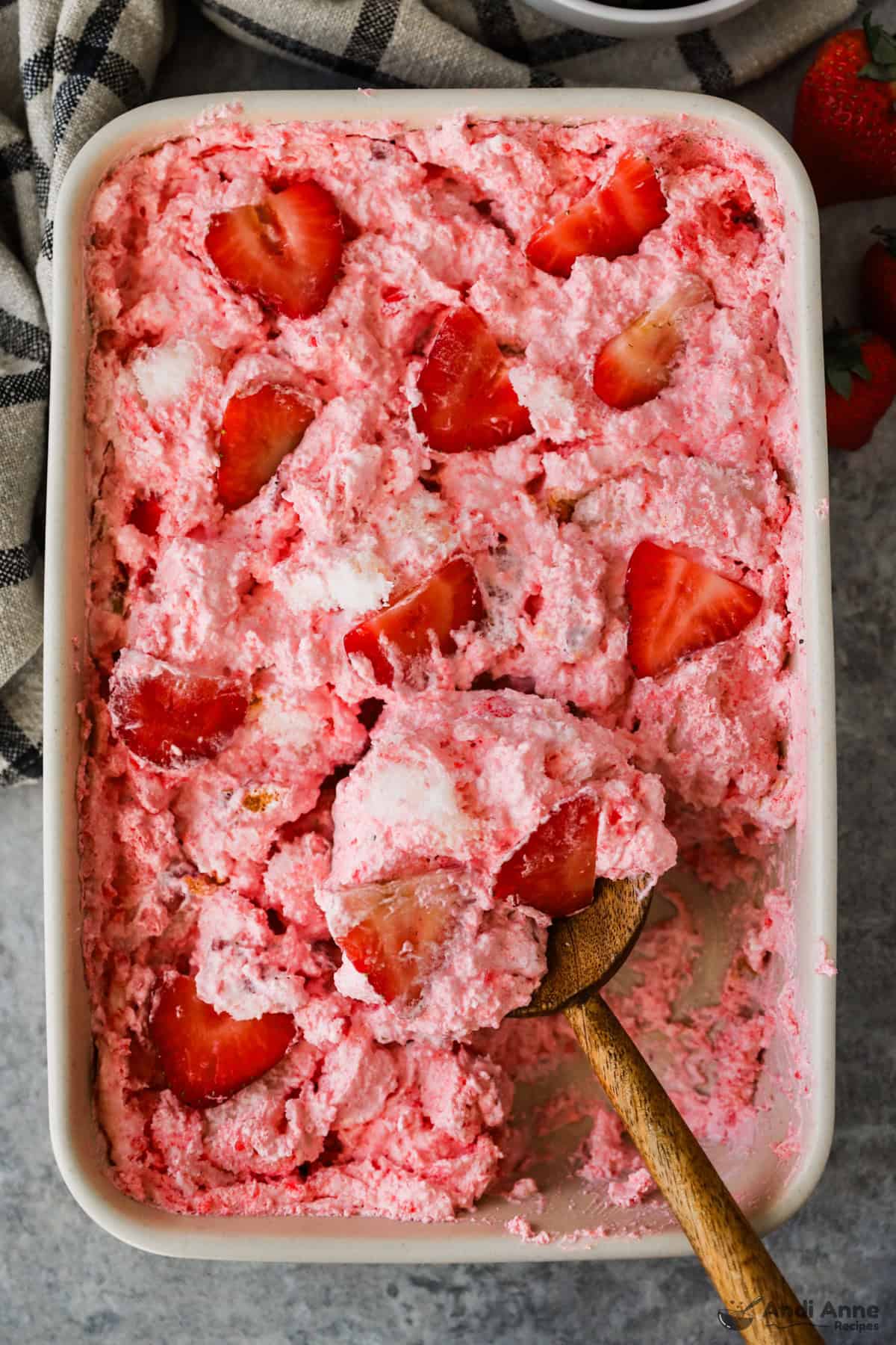A baking dish with strawberry angel food cake dessert topped with sliced strawberries.