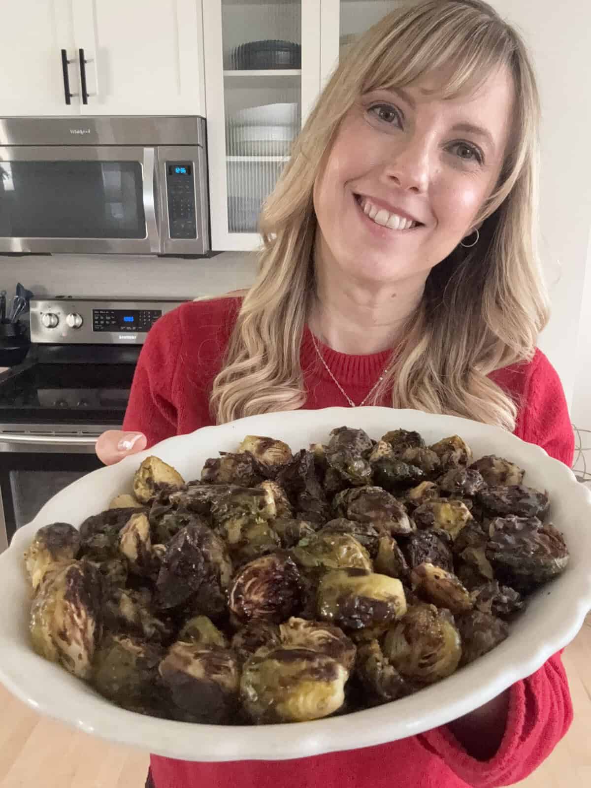 Andi Anne holding a plate of honey balsamic brussels sprouts