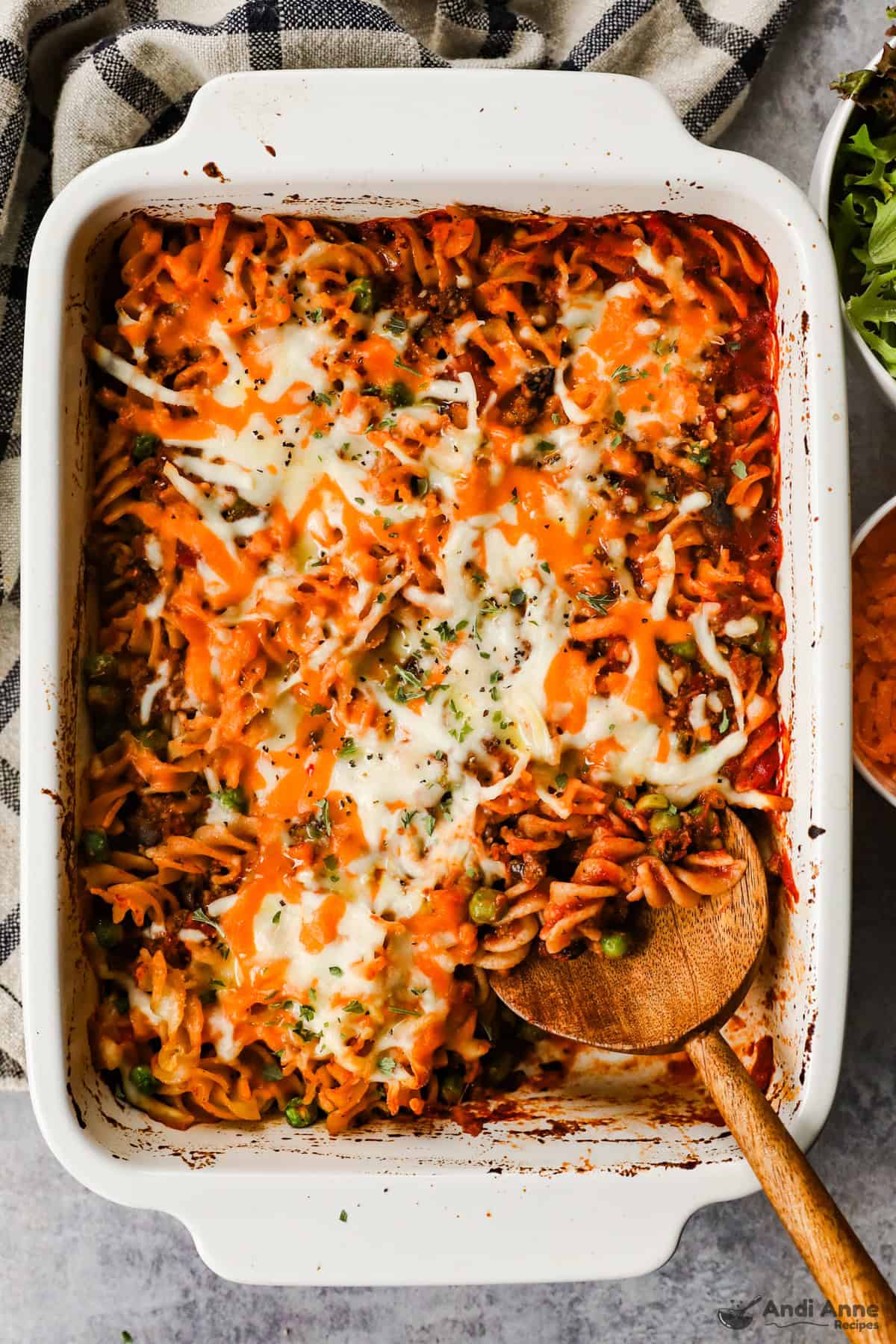 hamburger casserole in white casserole dish with wood spoon