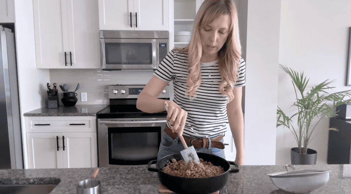 Andi in kitchen with skillet of ground beef on counter