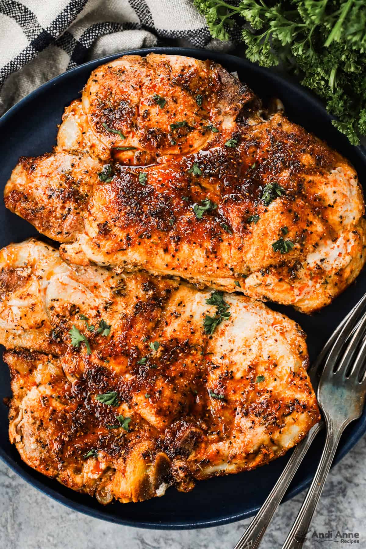 A plate with two air fryer pork chops and two forks.