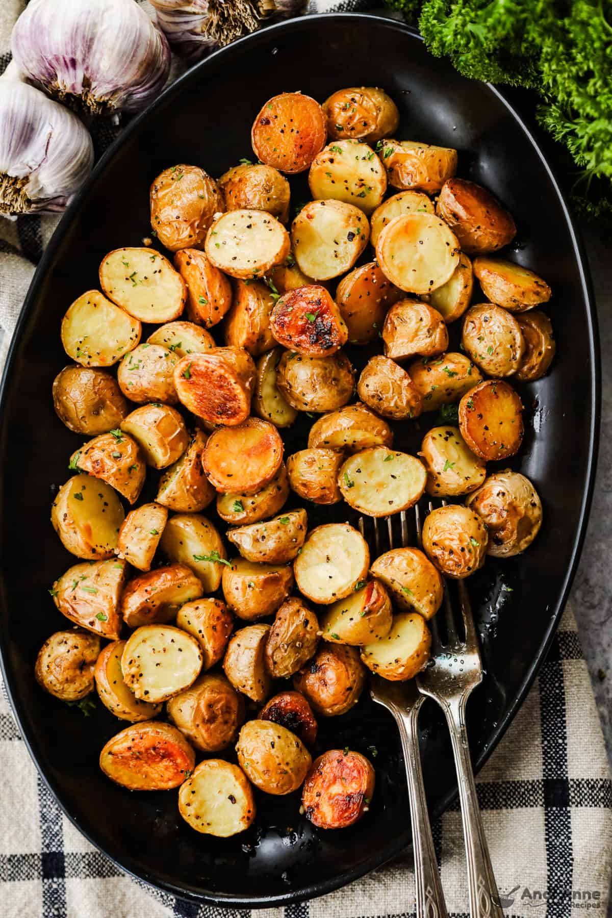 A serving dish with crispy roasted baby potatoes and two forks.