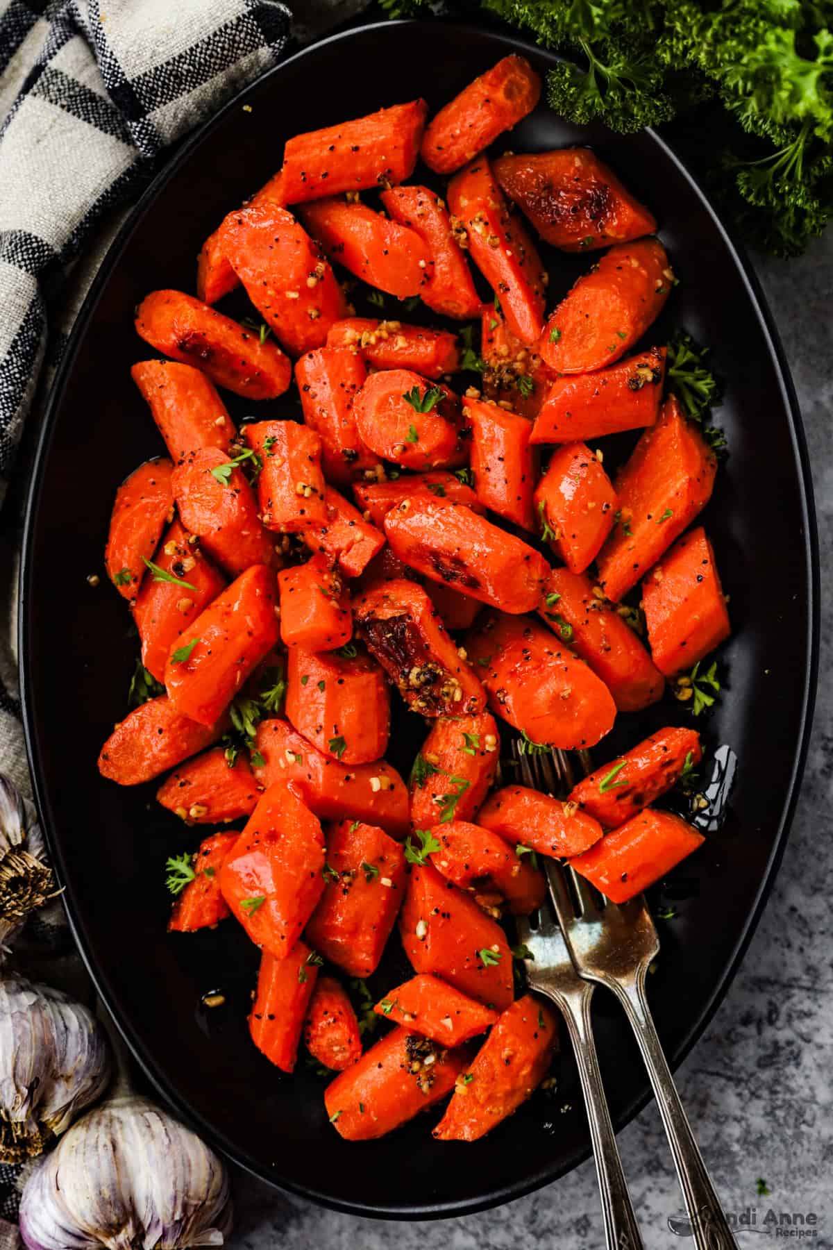 Roasted carrots with garlic on a serving dish with two forks.