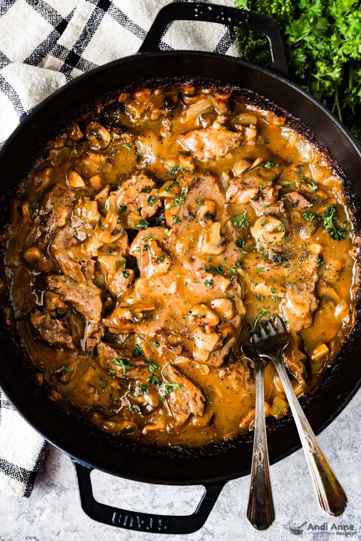 Round steak and gravy in the braising pan with two forks.