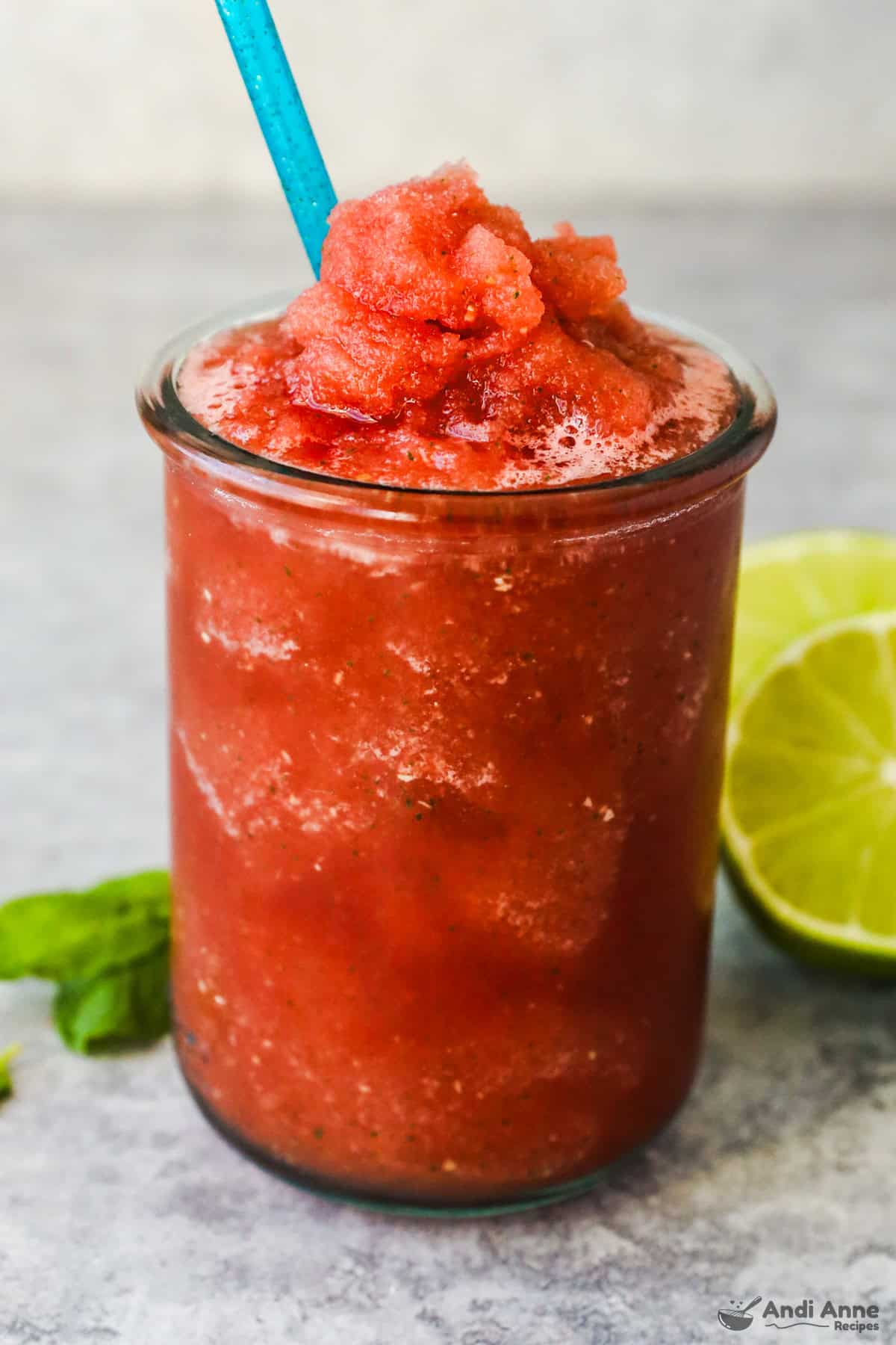 A glass of watermelon slushie with a straw.